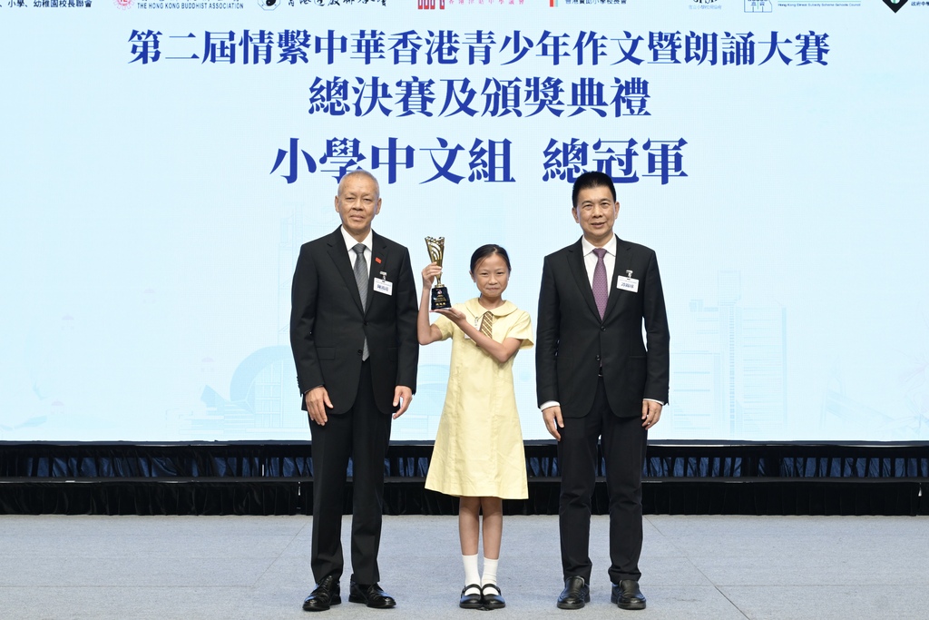 附图5：基金会会长谭锦球及主席陈鸿道向小学中文组总冠军张梓琳颁发奖杯