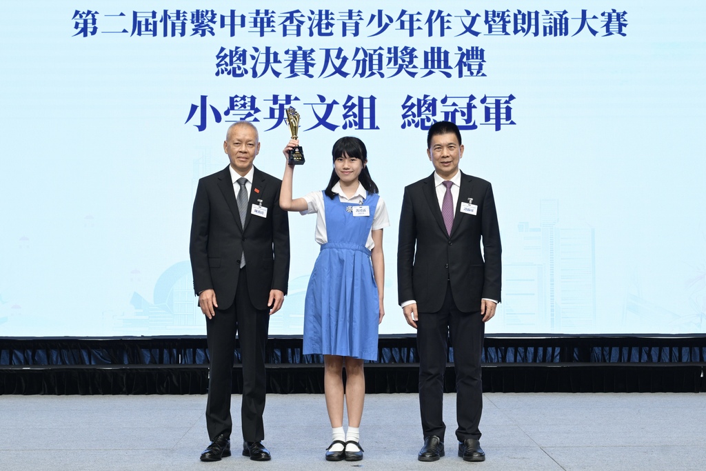 附图6：基金会会长谭锦球及主席陈鸿道向小学英文组总冠军冯靖霖颁发奖杯