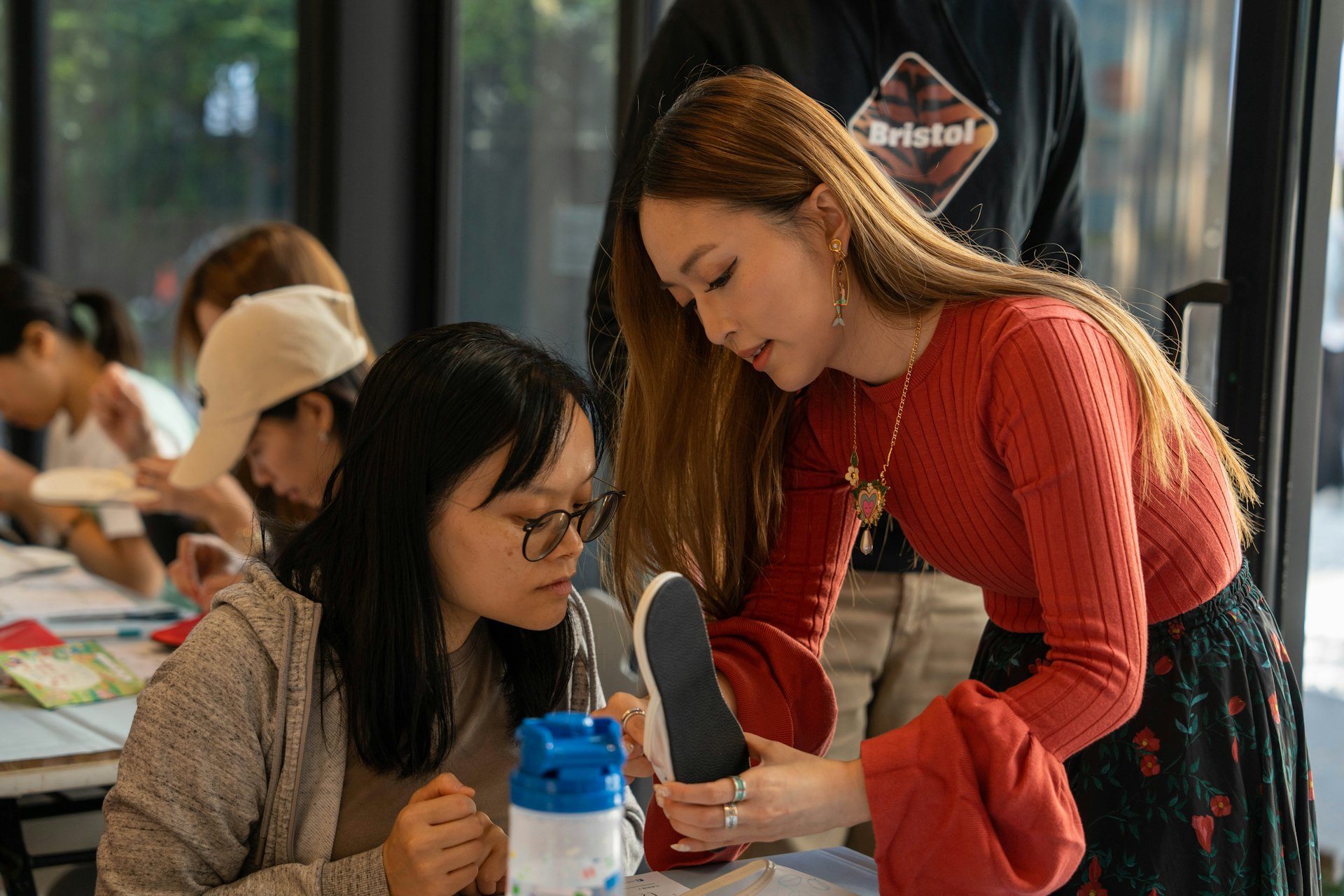 “非物质文化遗产市集2025”11月22日及23日于北角油街实现举办，绣花鞋第三代传人及插画家王嘉琳与工作坊参与者交流。（主办机构提供图片）