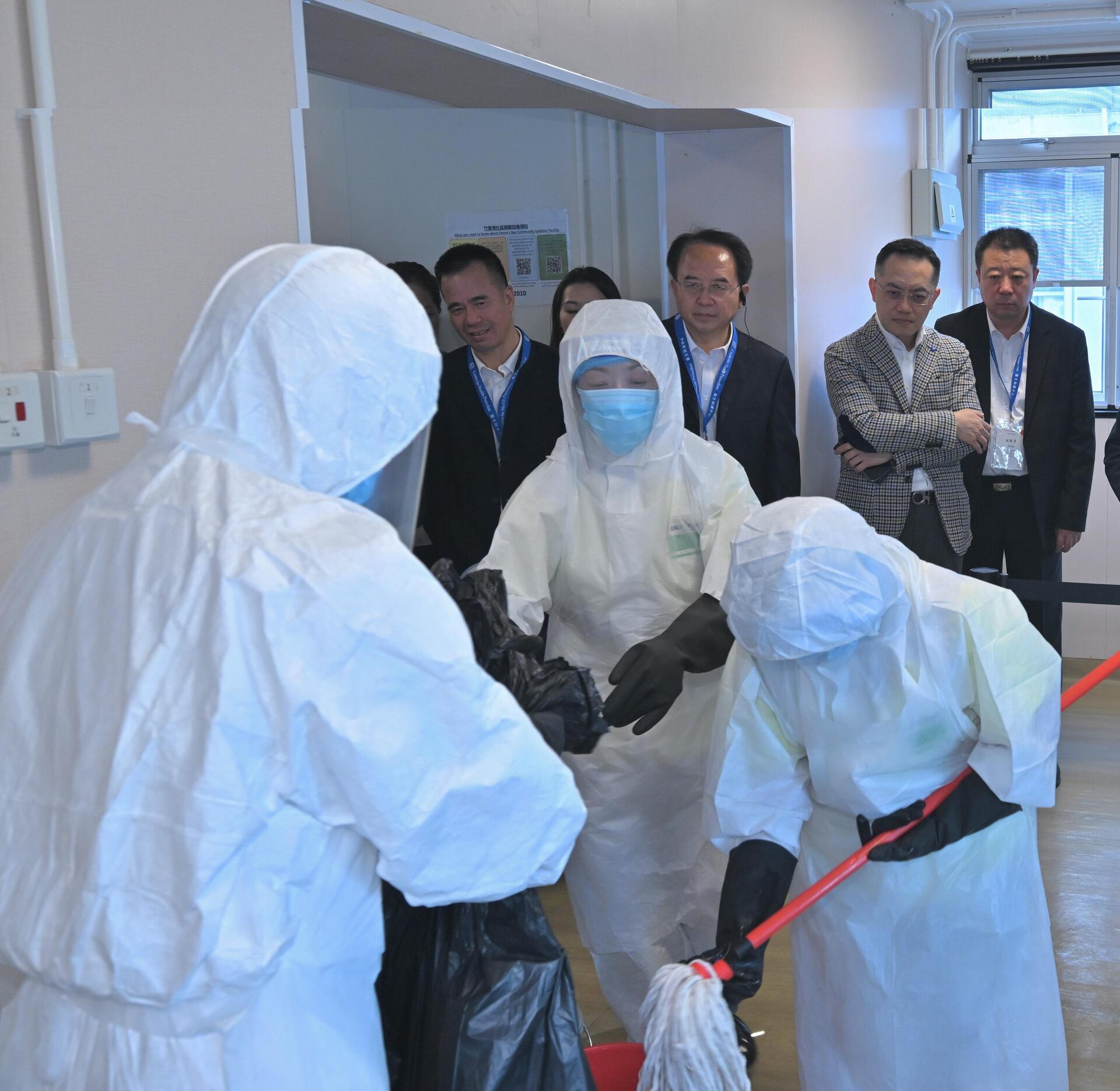 衞生署衞生防護中心今日(十一月二十五日)聯同多個政府部門舉行代號「紫水晶」的公共衞生演習,以提升中心和相關政府部門處理埃博拉(伊波拉)病個案時的應變能力,並提高持份者對處理突發公共衞生事件的意識。為強化與中國內地及國際交流,此次演習亦邀請了來自國家衞生健康委員會、國家疾病預防控制局、陝西省、湖北省、廣東省、粵港澳大灣區內地城市、澳門特別行政區和新加坡衞生當局的20多名專家,以觀察員身分出席。圖示食物環境衞生署人員進行清潔和消毒程序。衞生署署長林文健醫生(後排右二)和多位觀察員在旁視察。