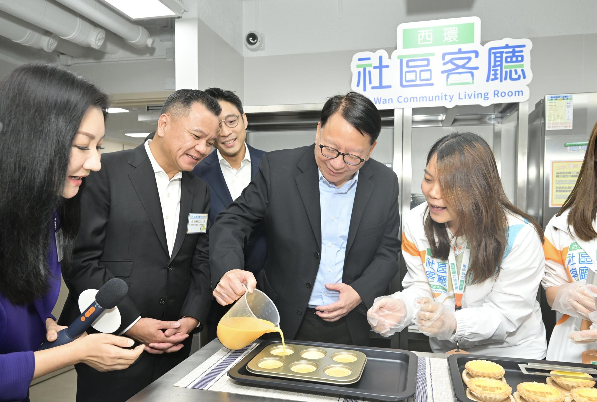 政务司司长陈国基参观西环社区客厅乐厨阁，并参与试制蛋挞。