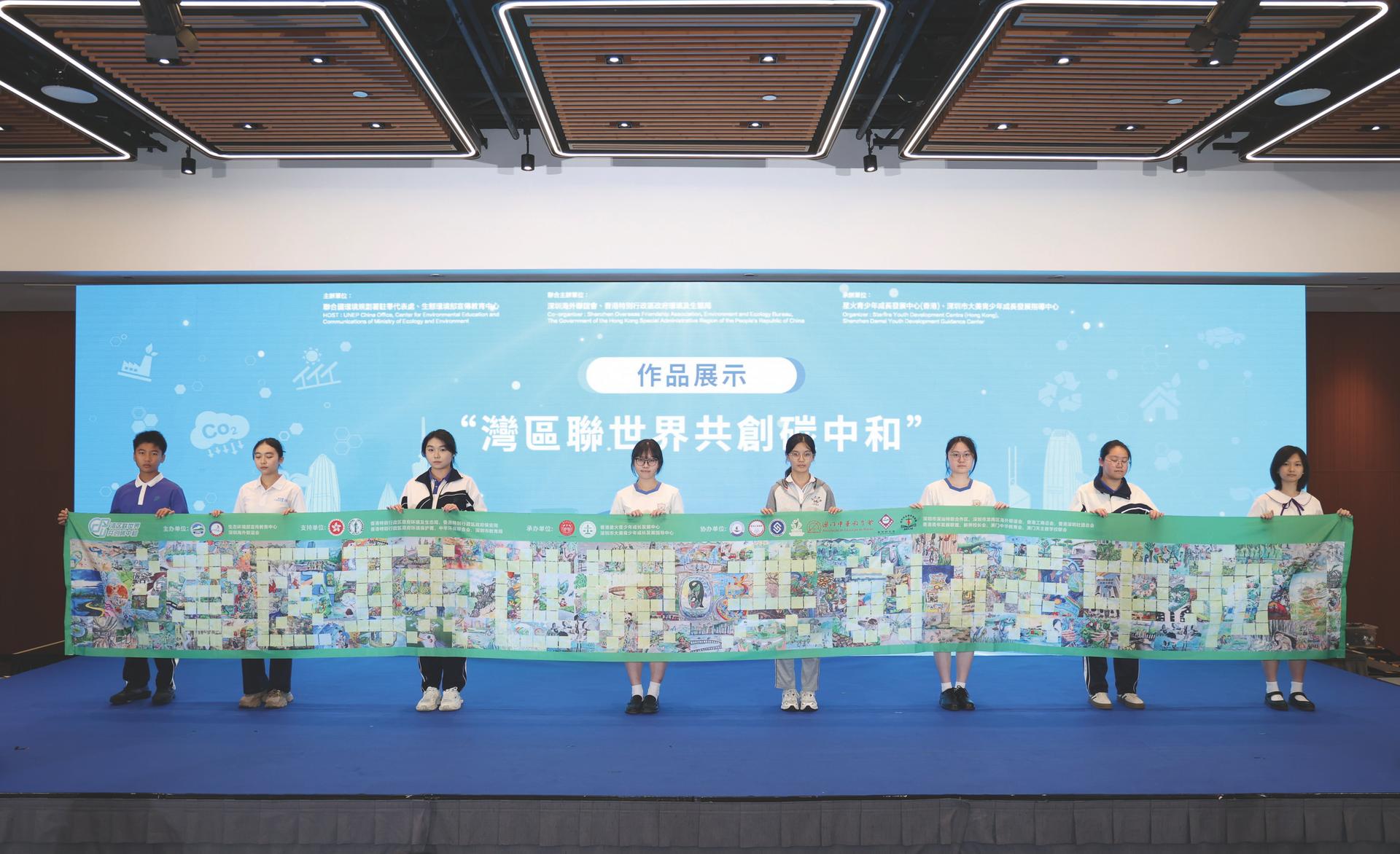 2025年10月29日，在香港举办的联合国中国青少年环境大会上，参与活动的学生展示“湾区联世界 共创碳中和”作品（图：新华社）