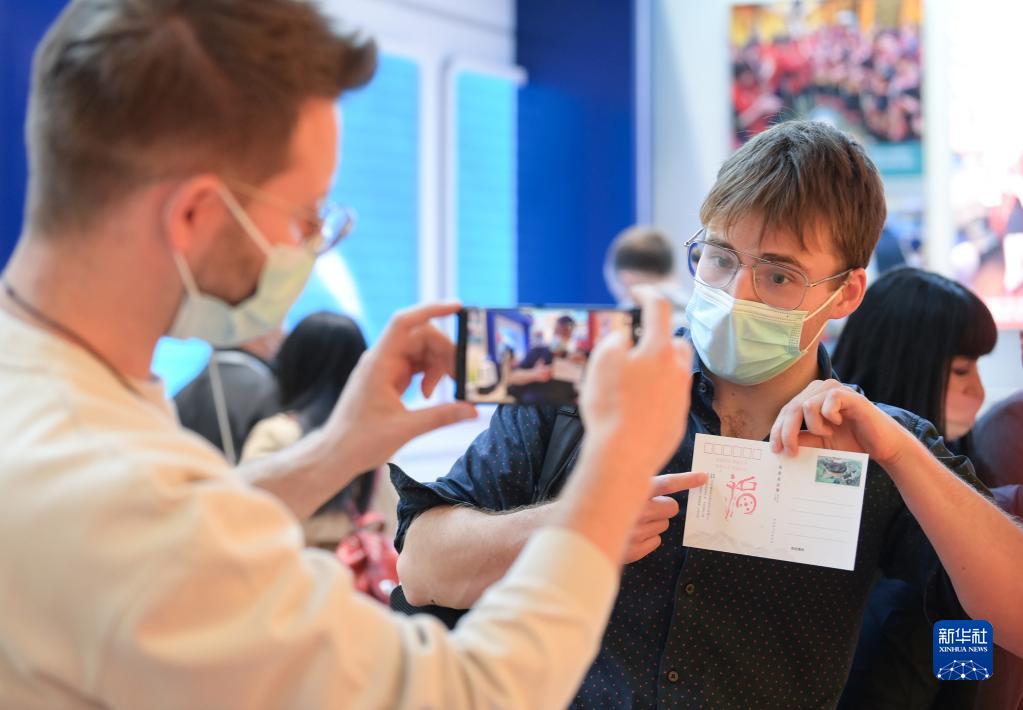 10月27日,外國嘉賓在互動體驗展台前拍攝在明信片上蓋的印戳。新華社記者 李賀 攝 1129084435_16668910744701n