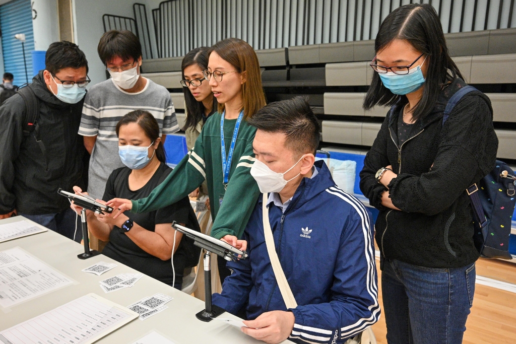圖示選舉事務處人員向投票站工作人員講解使用電子選民登記冊系統發出選票的程序。 P2023113000354_photo_1256909