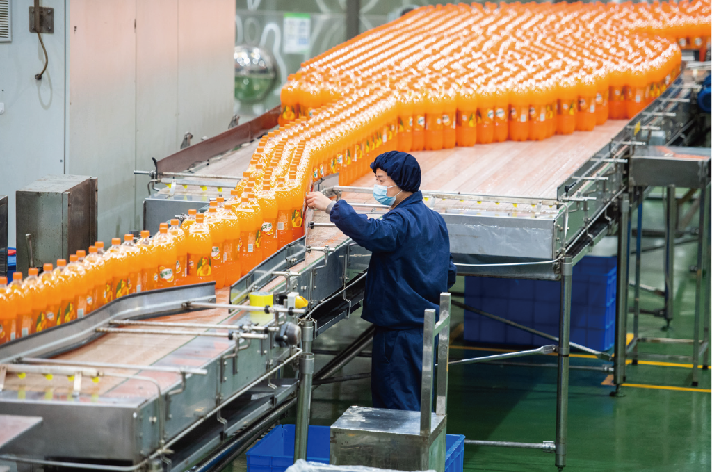 我国食品安全总体形势趋稳向好。图为湖南某食品加工企业开足马力忙生产,工作人员在车间检查饮料品质(图:新华社) WX20230905-190223@2x
