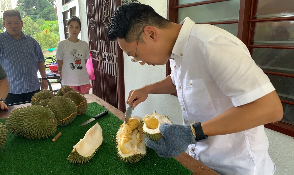 12 阿耀(右一)为客人开榴莲